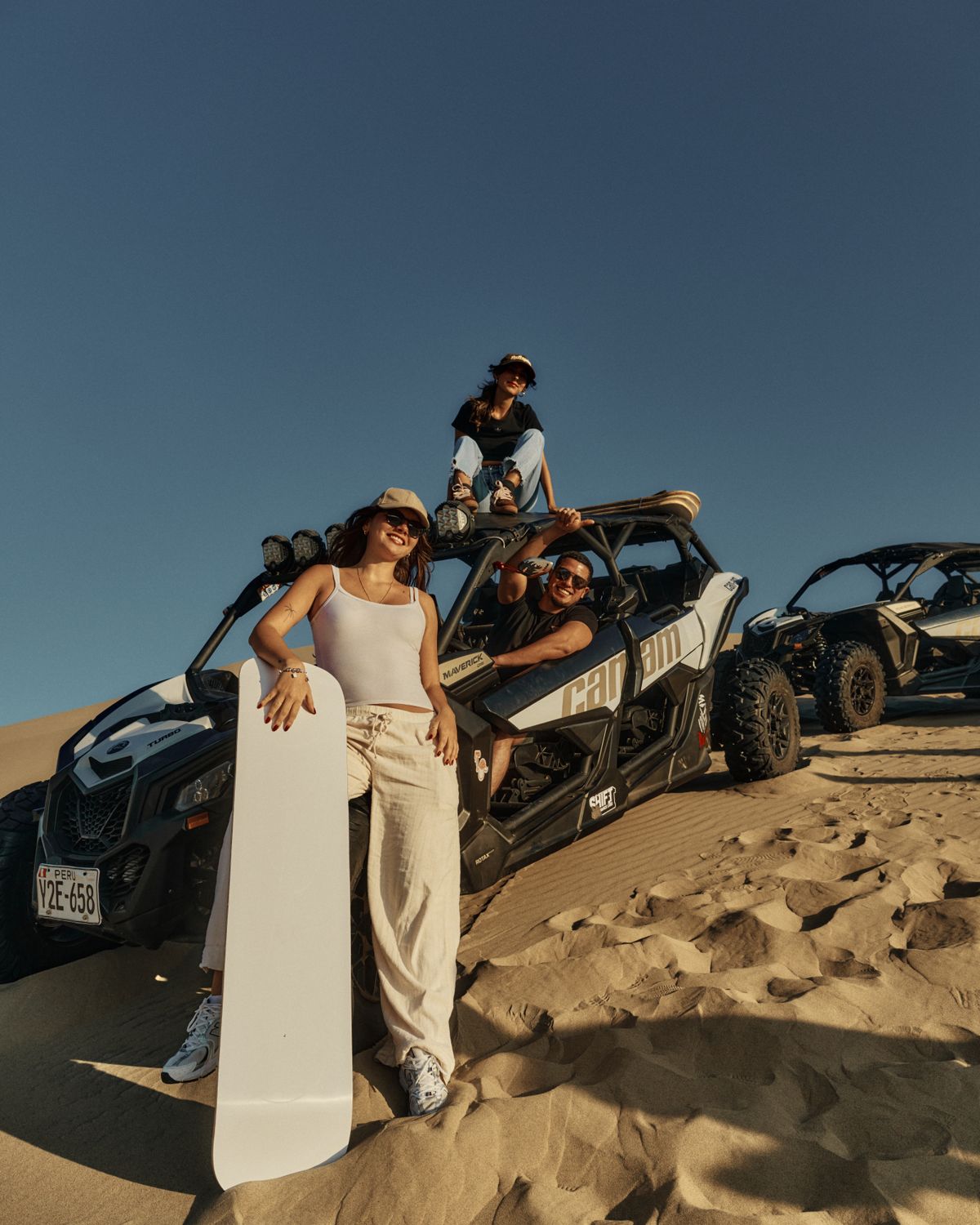 Guests with sandboards and vehicles on the dunes