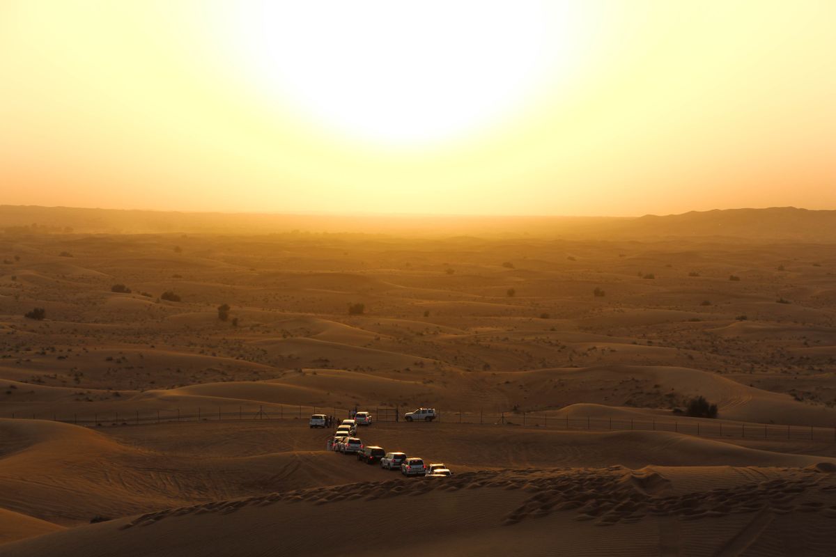 Vehicles crossing the dunes at dusk near the camp