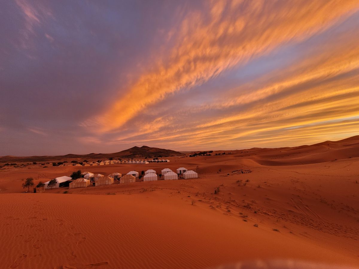 Camp tents under a blazing sunset sky