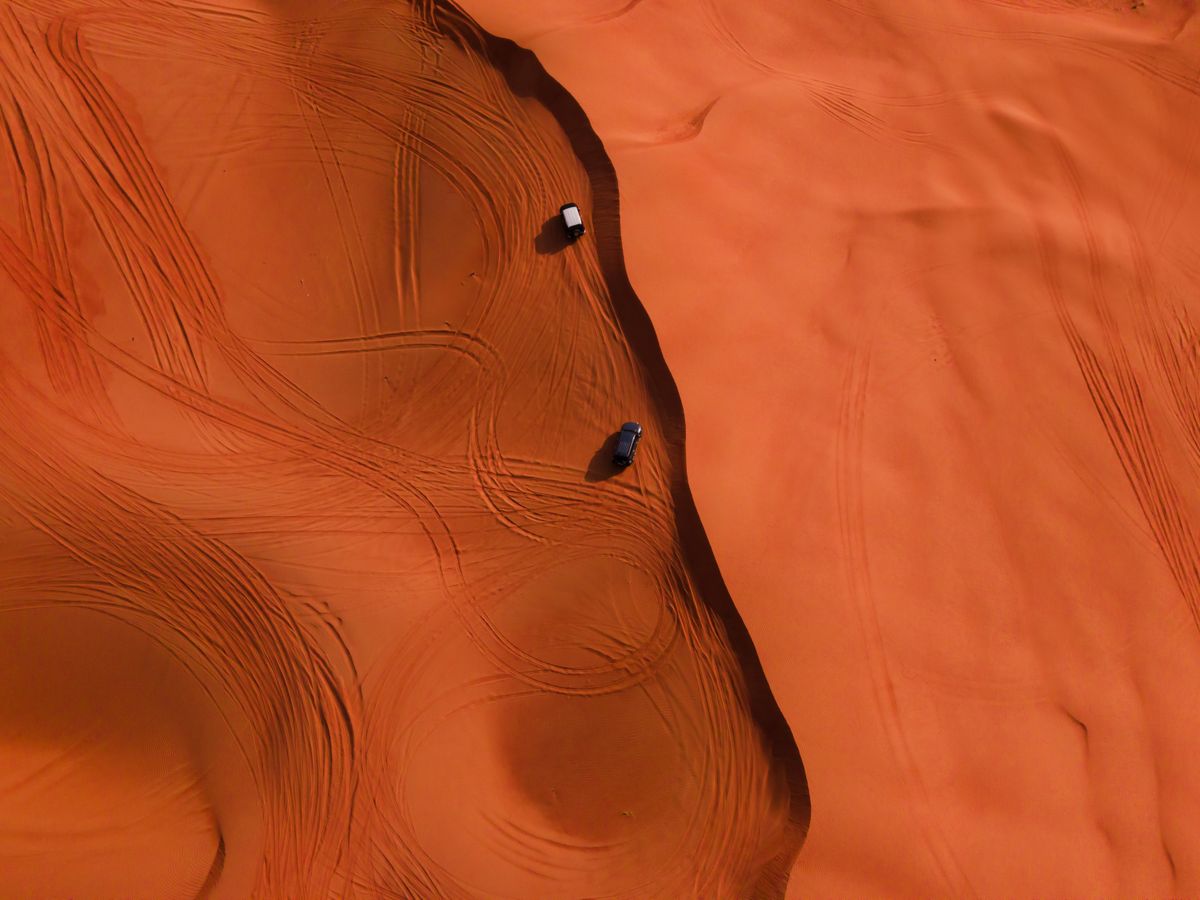The convoy’s tracks winding over wind-rippled dunes