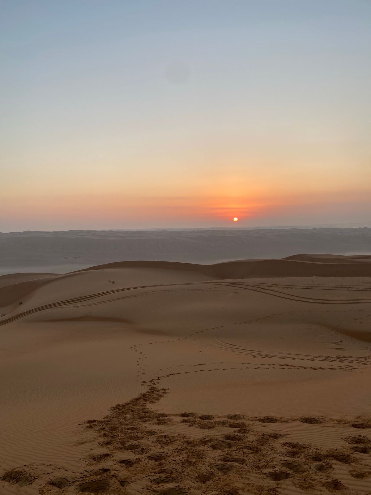 Footprints leading over the sand towards the setting sun