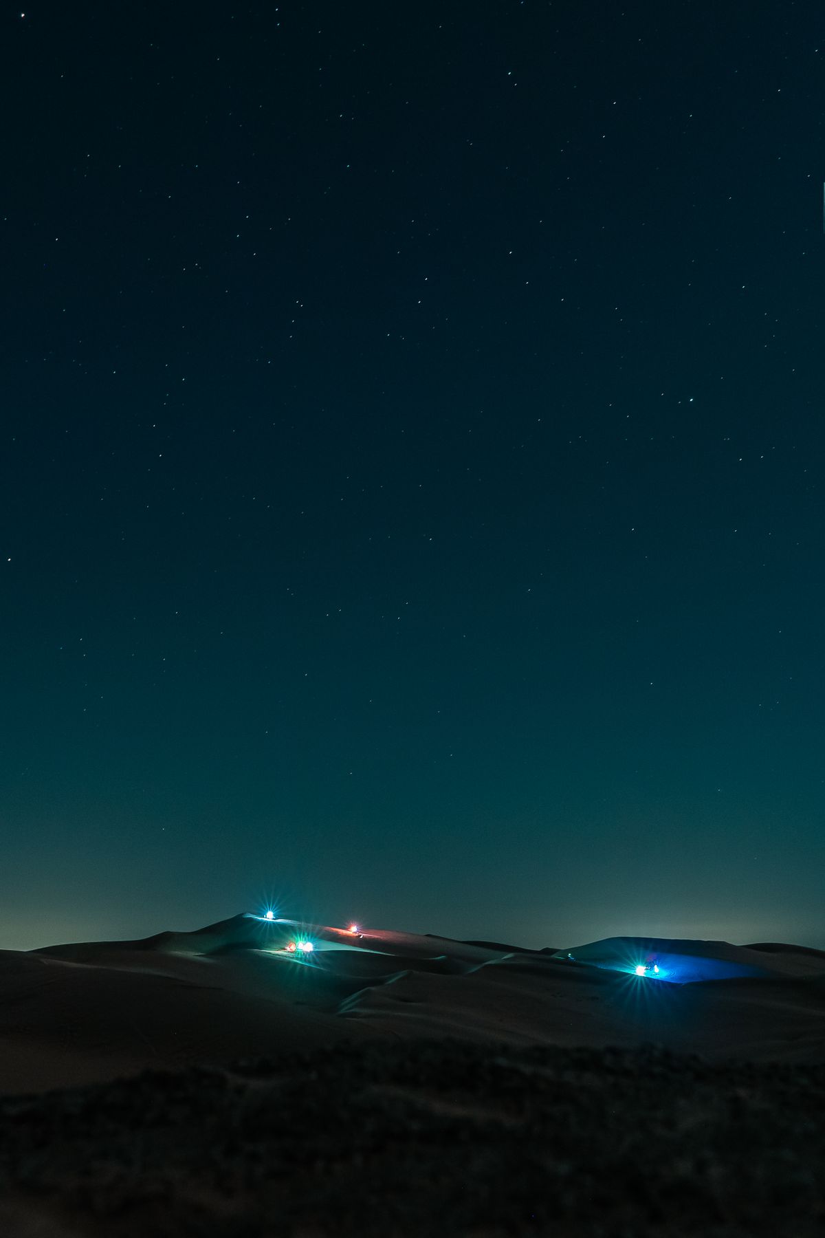 Stars over the dunes with the camp lights below