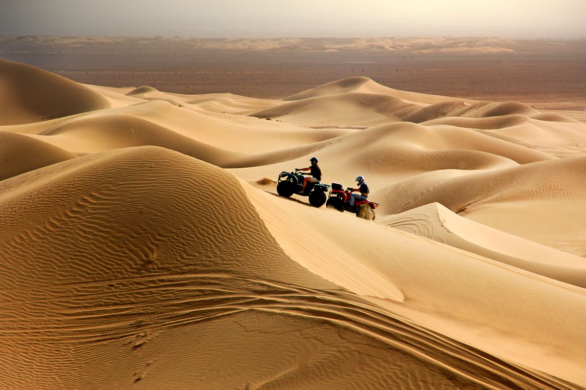 A quad bike kicking up sand on an open dune