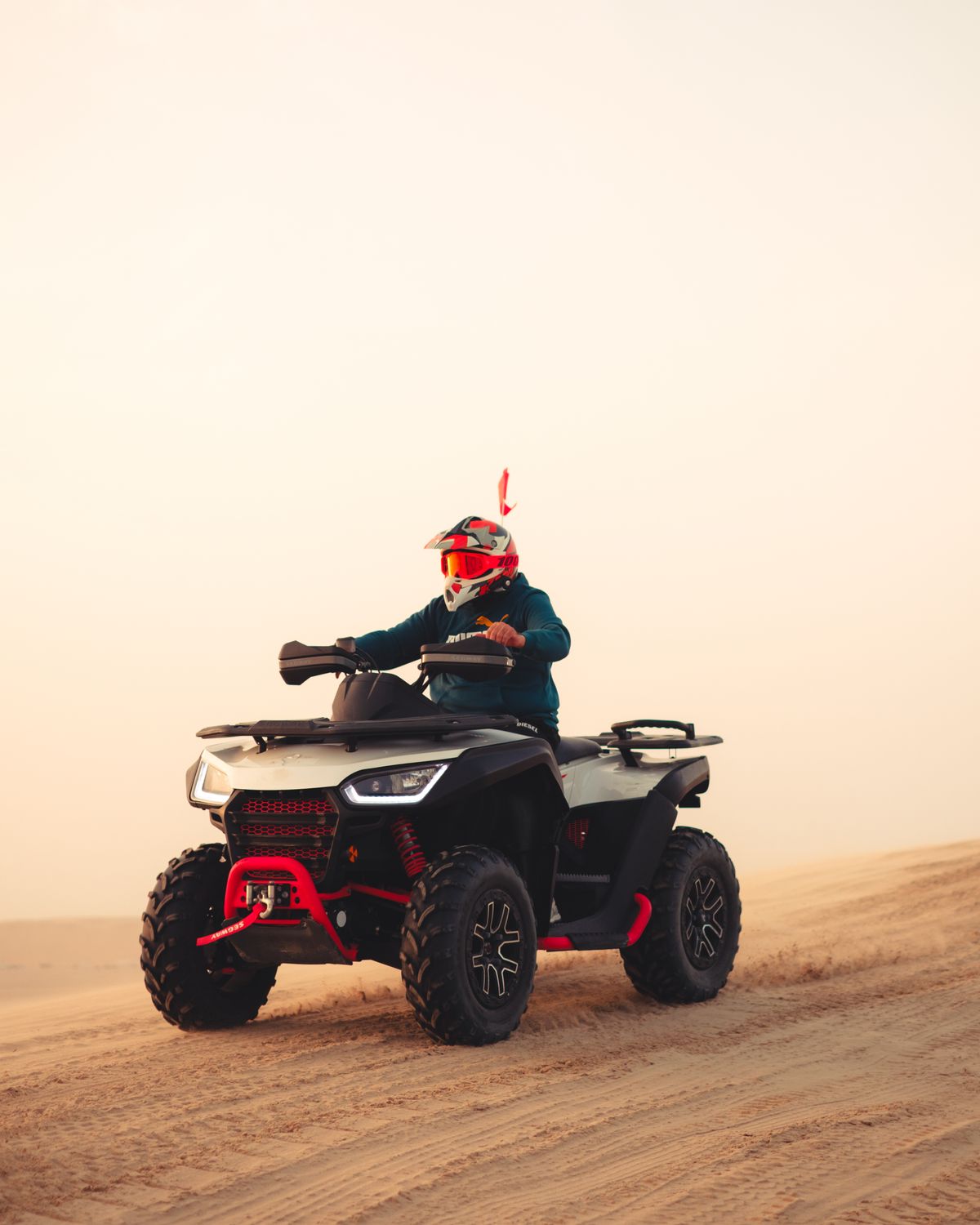 A rider silhouetted on a dune ridge at sunset