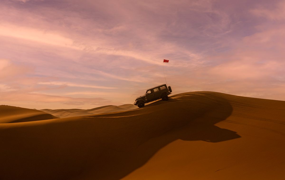The support 4×4 climbing a dune under an evening sky
